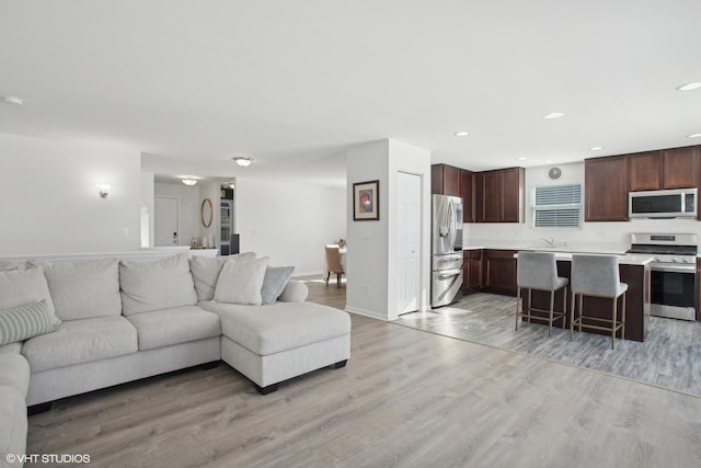 living area with light wood-style floors, recessed lighting, and baseboards