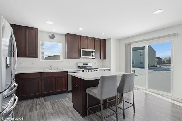 kitchen with a kitchen island, a breakfast bar, stainless steel appliances, light countertops, and a sink