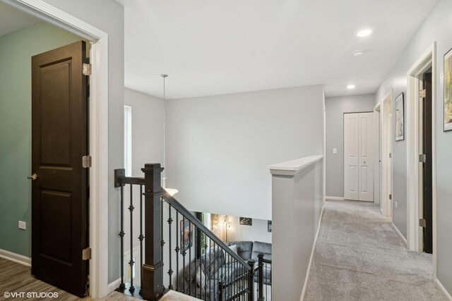 hallway featuring light colored carpet, recessed lighting, baseboards, and an upstairs landing