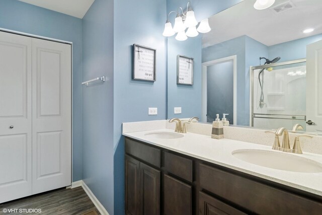 full bathroom with double vanity, a shower stall, visible vents, and a sink