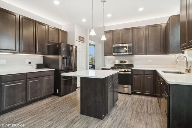 kitchen featuring a center island, pendant lighting, stainless steel appliances, light countertops, and a sink