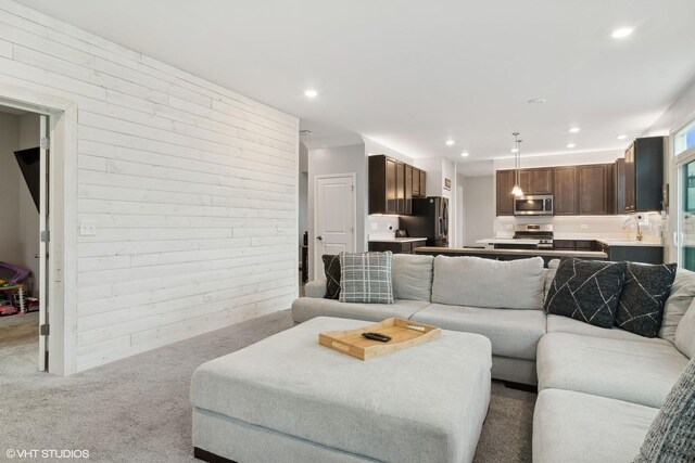 living area featuring recessed lighting, light carpet, and wooden walls