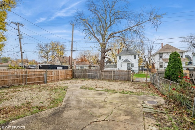 view of yard with a patio area, a fenced backyard, and a residential view