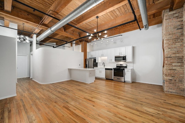 kitchen with stainless steel appliances, light countertops, white cabinetry, and pendant lighting