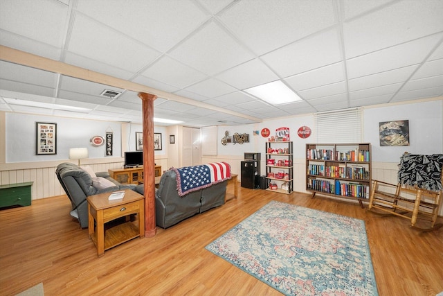 living room with wood finished floors, a drop ceiling, and wainscoting