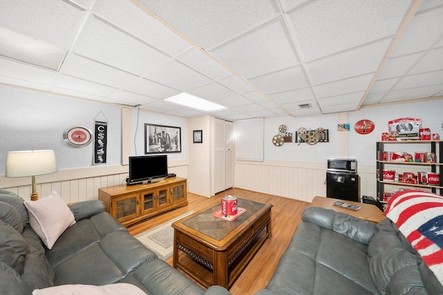 living room featuring a wainscoted wall, a paneled ceiling, and wood finished floors