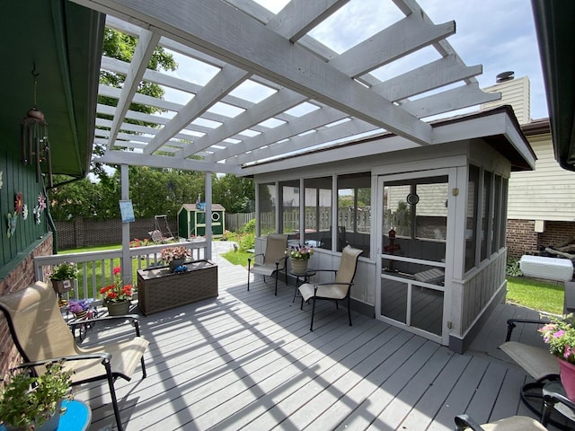 wooden terrace with an outbuilding, a pergola, a storage unit, and a sunroom