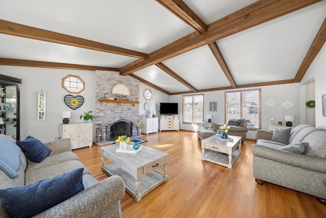 living room with lofted ceiling with beams, a brick fireplace, and light wood-type flooring