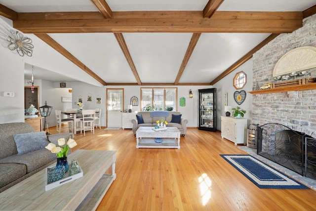 living area featuring light wood-style flooring, a fireplace, and lofted ceiling with beams