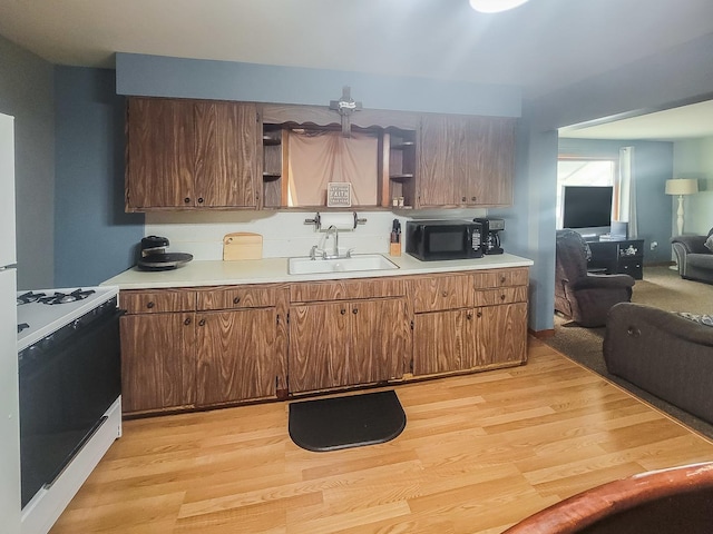 kitchen featuring black microwave, a sink, light countertops, open shelves, and white gas range