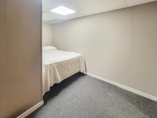 unfurnished bedroom with a paneled ceiling, baseboards, and carpet