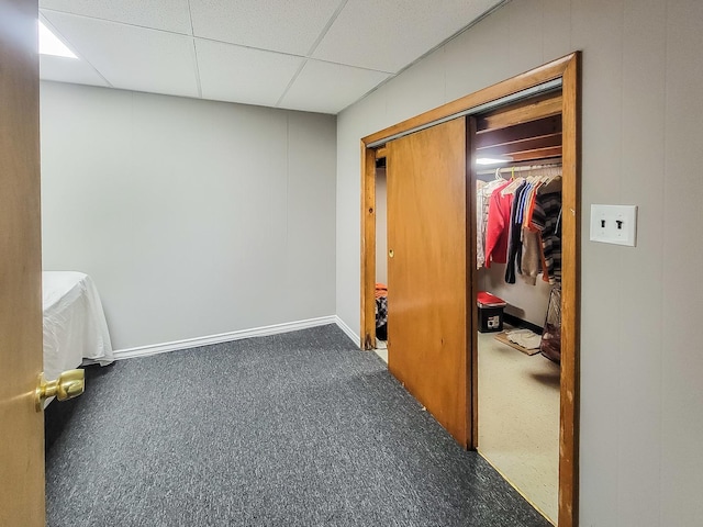 carpeted bedroom featuring a closet, a paneled ceiling, and baseboards