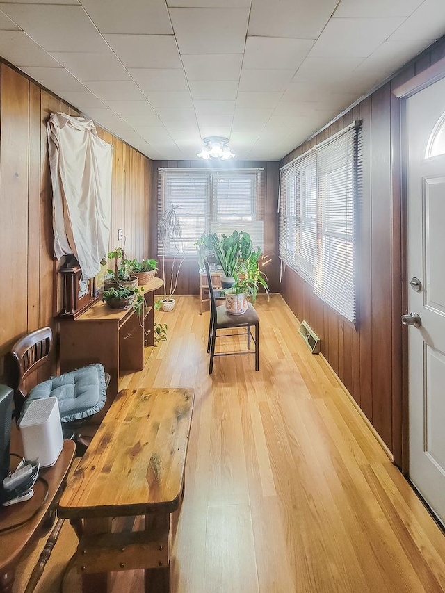 interior space with light wood-type flooring, wood walls, and visible vents