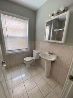 bathroom featuring toilet, a wainscoted wall, tile patterned flooring, and tile walls