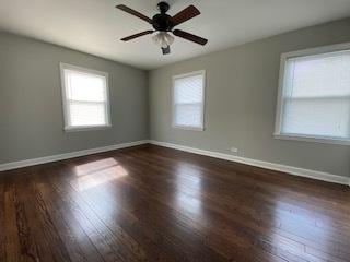 unfurnished room with a ceiling fan, dark wood-style flooring, and baseboards