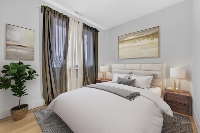 bedroom featuring light wood-type flooring, visible vents, and baseboards