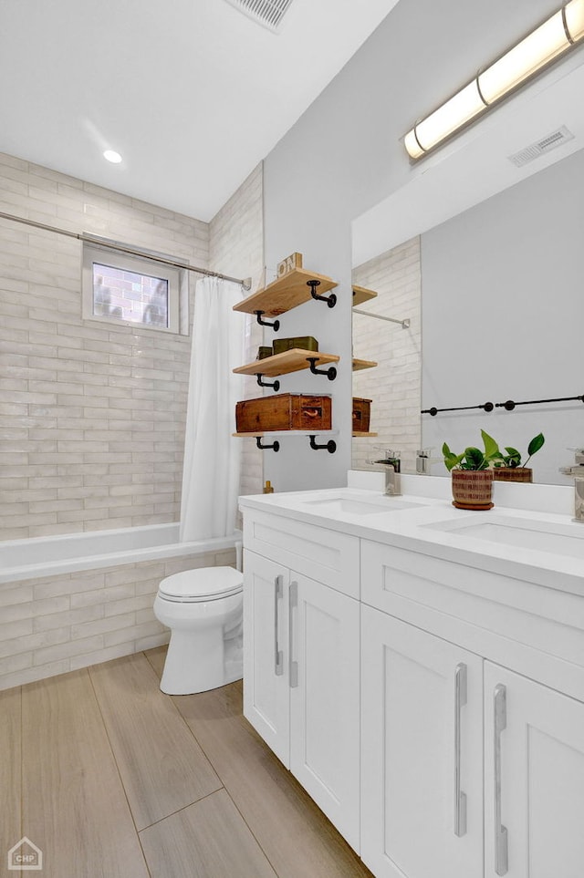 bathroom featuring visible vents, toilet, wood tiled floor, tiled shower / bath combo, and vanity