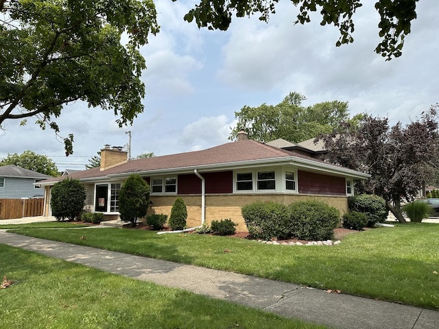 ranch-style house with a front lawn, a chimney, fence, and brick siding