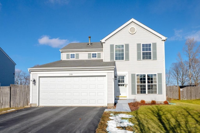 traditional-style home featuring driveway, an attached garage, fence, and a front yard