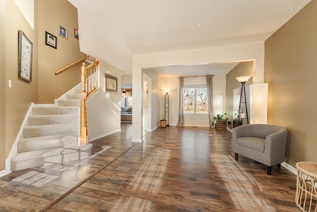 foyer entrance with stairs, wood finished floors, and baseboards