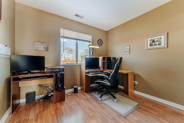 office space with light wood-style floors, visible vents, and baseboards