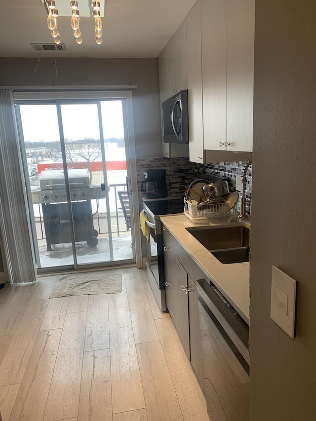 kitchen with visible vents, range with electric cooktop, dishwashing machine, light countertops, and a sink