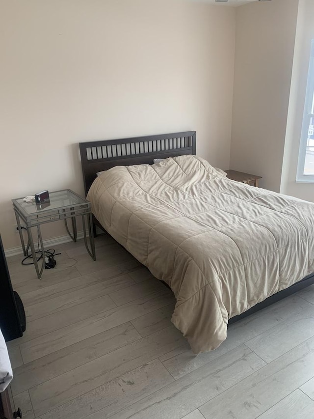 bedroom with light wood-type flooring and baseboards