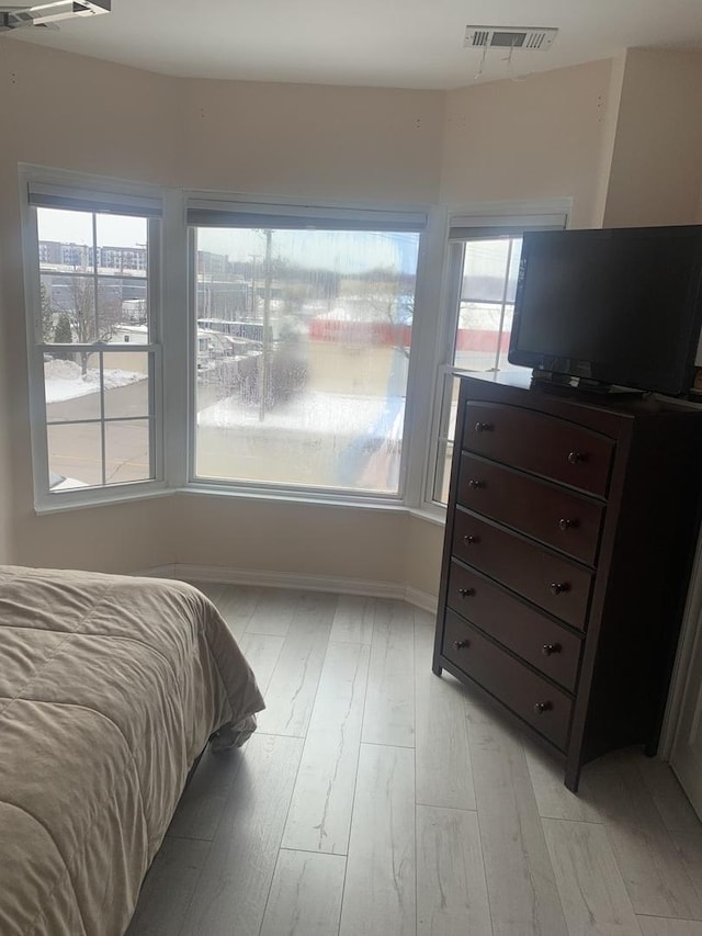 bedroom featuring light wood-style flooring, multiple windows, visible vents, and baseboards