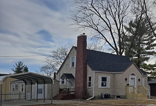 view of front of house featuring a carport, roof with shingles, a chimney, and central air condition unit