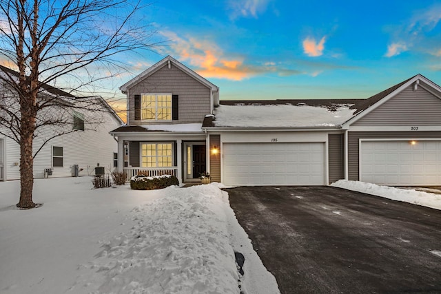 traditional home with driveway, a porch, and an attached garage