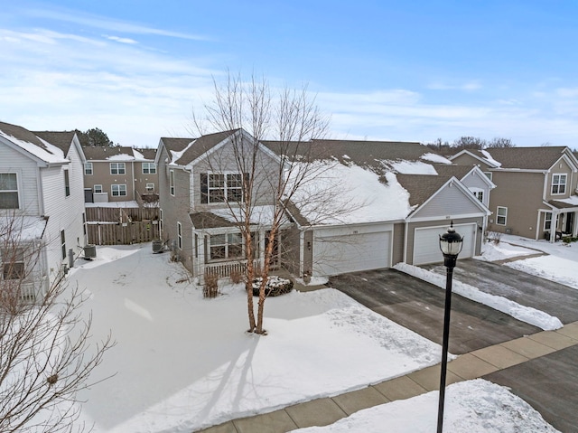 view of front of house featuring an attached garage, driveway, a residential view, and fence