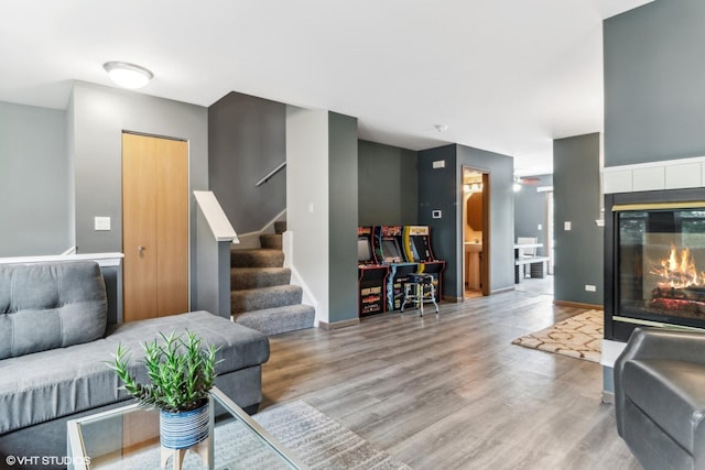 living area featuring stairway, baseboards, wood finished floors, and a tiled fireplace