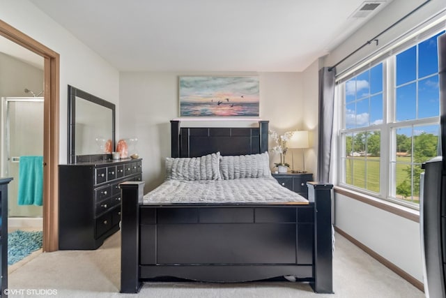 bedroom with light colored carpet, visible vents, ensuite bathroom, and baseboards