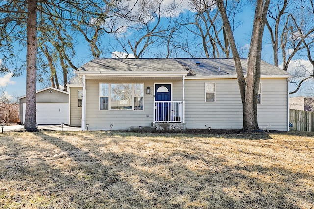 ranch-style home with a garage, an outbuilding, fence, and a front lawn