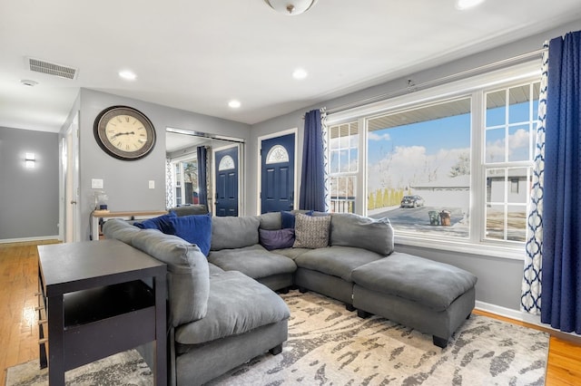 living room featuring baseboards, visible vents, wood finished floors, and recessed lighting