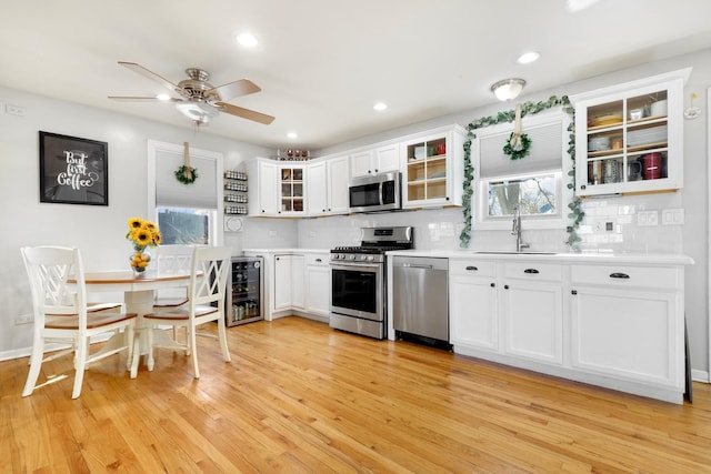 kitchen with white cabinets, glass insert cabinets, appliances with stainless steel finishes, light countertops, and a sink