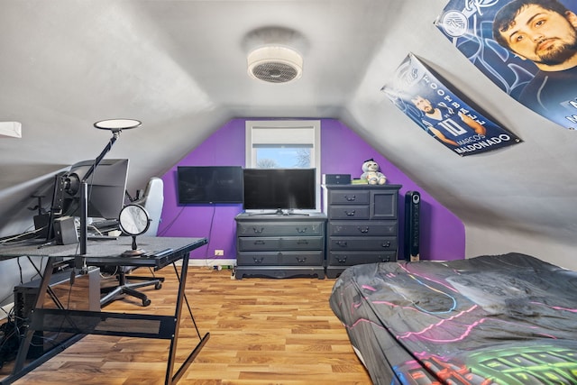 bedroom with vaulted ceiling and wood finished floors