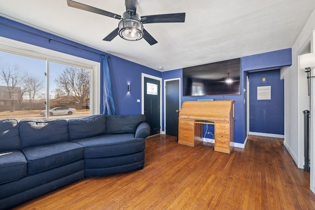 living area featuring dark wood finished floors, a ceiling fan, and baseboards