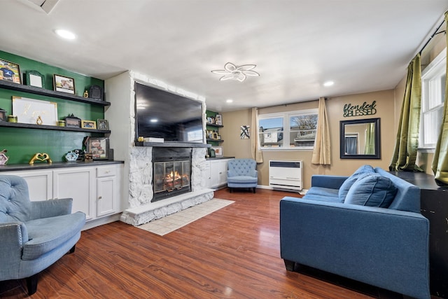 living room with heating unit, plenty of natural light, dark wood-style flooring, and a glass covered fireplace