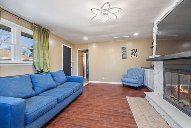 living room with recessed lighting, wood finished floors, baseboards, a glass covered fireplace, and attic access