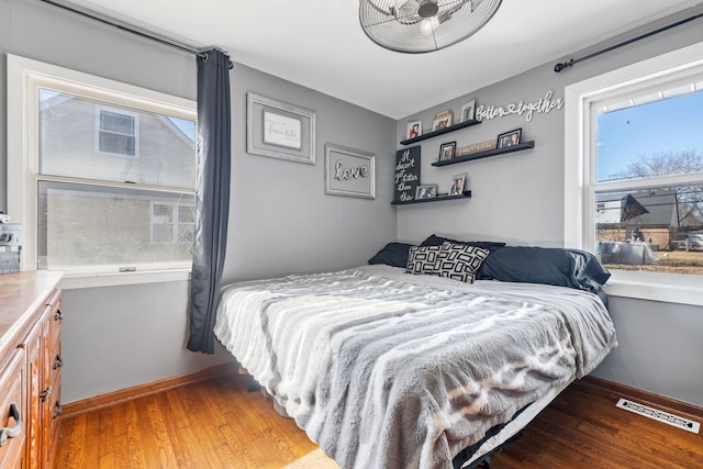 bedroom with baseboards, visible vents, and wood finished floors