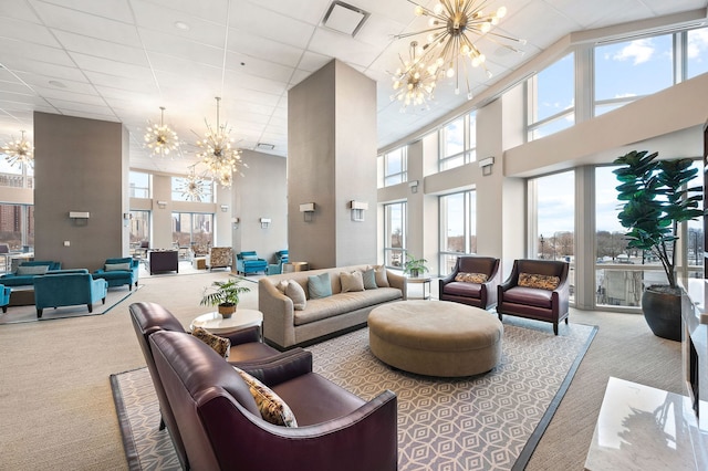 carpeted living room with a chandelier, visible vents, and a high ceiling