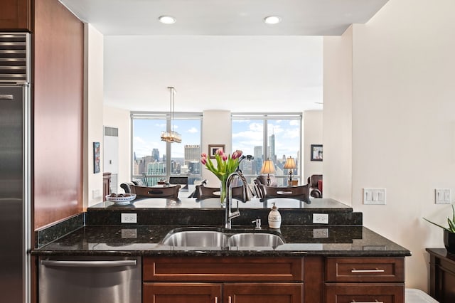 kitchen with a city view, dark stone countertops, stainless steel appliances, and a sink