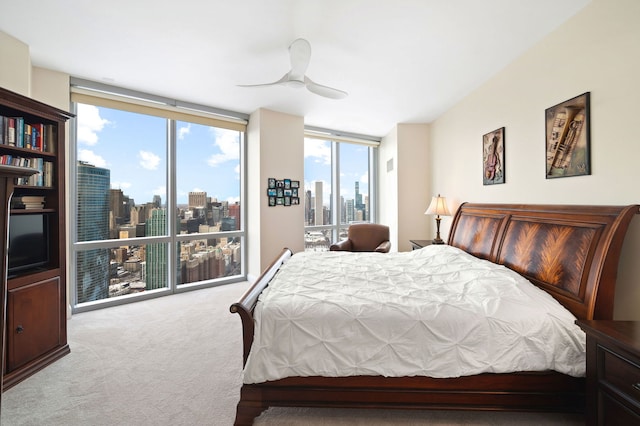 bedroom featuring a wall of windows, carpet, a ceiling fan, a view of city, and access to outside