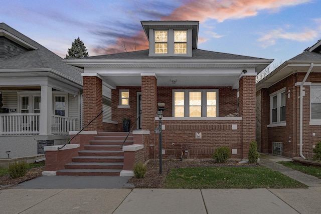 bungalow-style house with covered porch and brick siding