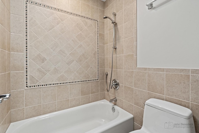 bathroom with toilet, bathtub / shower combination, and tile walls