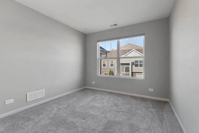 unfurnished room featuring carpet, visible vents, and baseboards