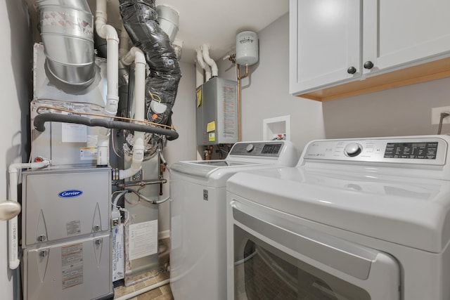 laundry room with heating unit, cabinet space, water heater, and washer and clothes dryer