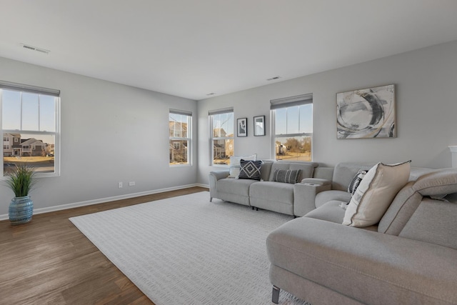 living area featuring dark wood finished floors, plenty of natural light, visible vents, and baseboards