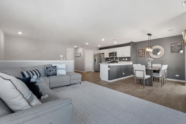 living room with wood finished floors, baseboards, visible vents, an inviting chandelier, and recessed lighting